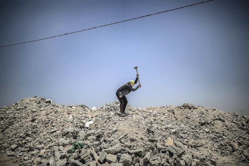 Workers break down the rubble of buildings destroyed during the May rocket attacks. Sanad Latefa for The National
