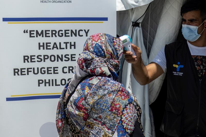 A health ministry official checks the temperature of a migrant before receiving the Johnson & Johnson vaccine in Lesbos. Reuters