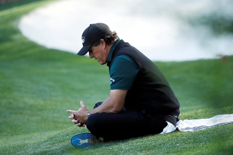 FILE PHOTO: Phil Mickelson of the U.S. sits in the grass on the 13th as he waits on players in his group to finish the hole during first round play of the 2018 Masters golf tournament at the Augusta National Golf Club in Augusta, Georgia, U.S., April 5, 2018. REUTERS/Mike Segar/File Photo