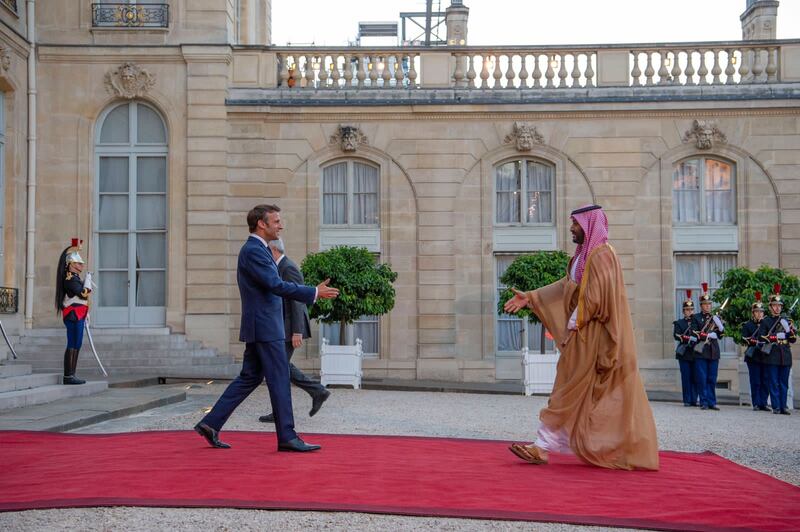 Mr Macron and Prince Mohammed walk to greet each other. 