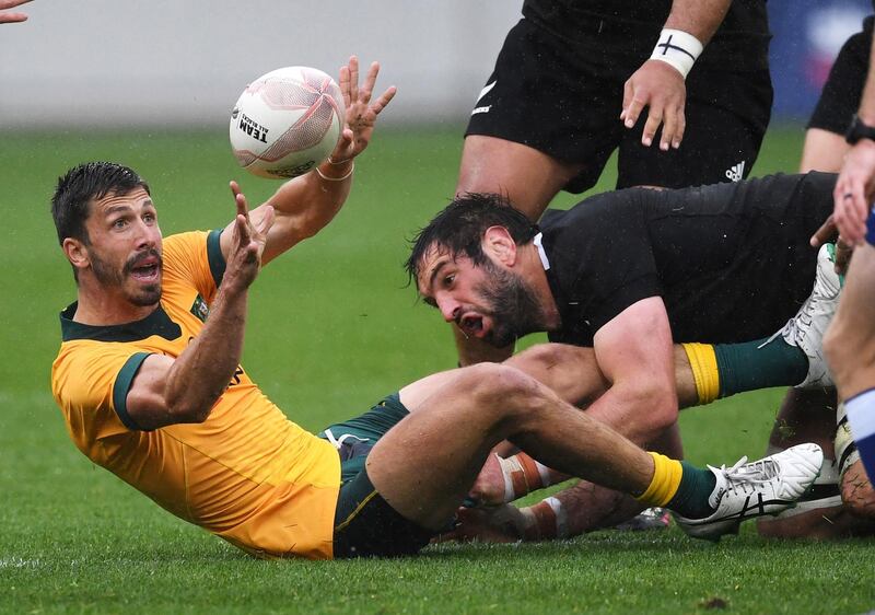 Australia's Jake Gordon passes the ball in the tackle of New Zealand's Sam Whitelock during the Bledisloe Cup rugby game between the All Blacks and the Wallabies in Wellington, New Zealand. AP Photo