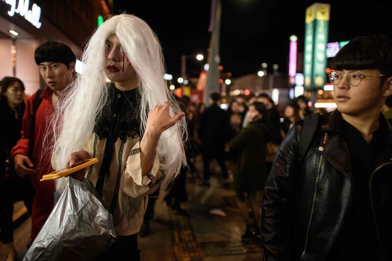 Revellers wearing Halloween make-up pose for a photo as they walk past bars and restaurants in the popular nightlife district of Itaewon in Seoul.  AFP