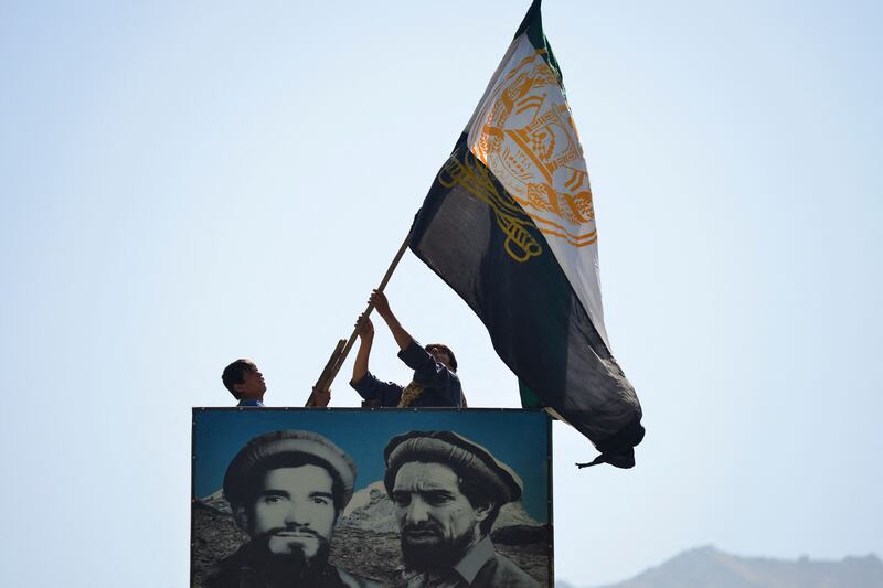 Afghans wave a flag above a portrait of the late Afghan resistance leader Ahmad Shah Massoud  in north-eastern Panjshir province, the only region of Afghanistan that has not yet fallen to the Taliban. AFP