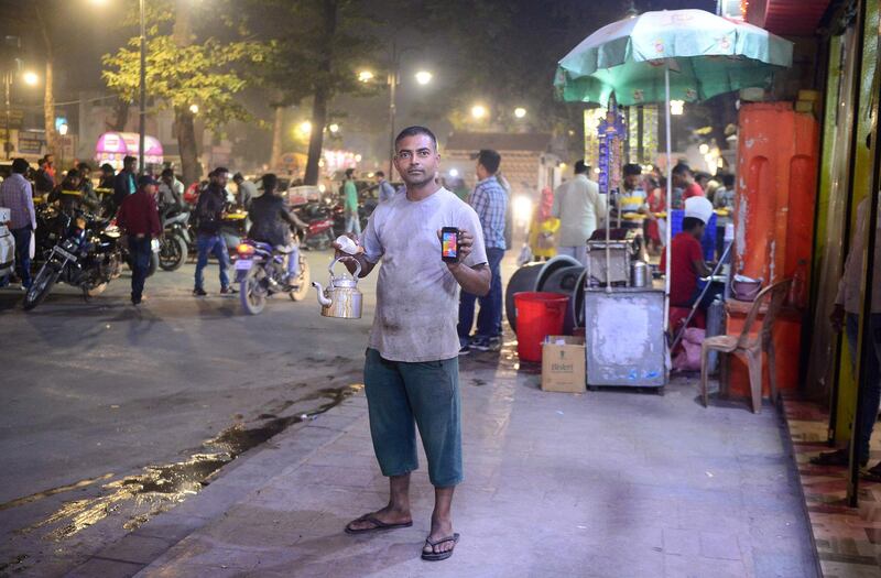 (FILES) In this file photo taken on November 10, 2018 an Indian tea seller Vikas Kesharwani, 35, poses with his smartphone at a market in Allahabad. / AFP / SANJAY KANOJIA
