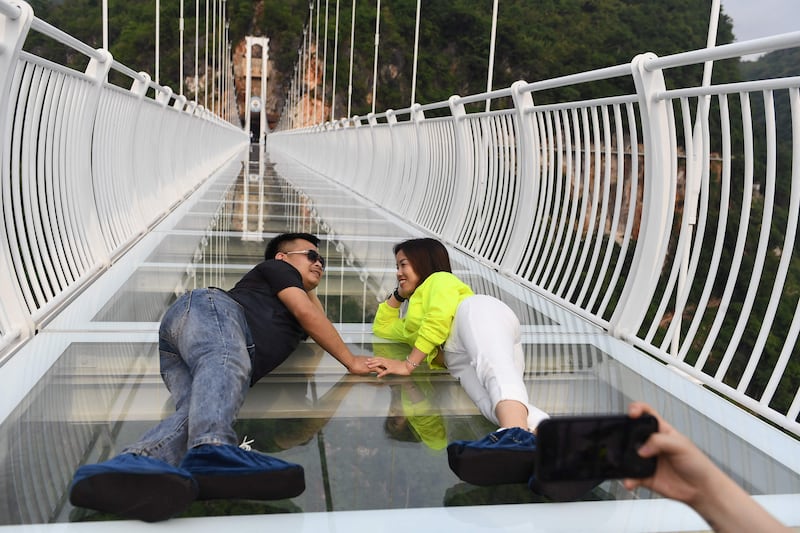 A couple take pictures on the bridge. 