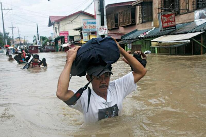 Residents wade through floodwater brought by monsoon rain, intensified by tropical storm Trami, in Kawit town of Cavite city, south of Manila August 19, 2013. Heavy rain in the Philippine capital forced the closure of government offices, schools, banks and most private companies on Monday, and residents in parts of the city and nearby provinces had to flee from their homes because of floods. At least three people were killed and two were missing in accidents caused by the rain and flooding, disaster and government officials said.   REUTERS/Romeo Ranoco (PHILIPPINES - Tags: DISASTER ENVIRONMENT)