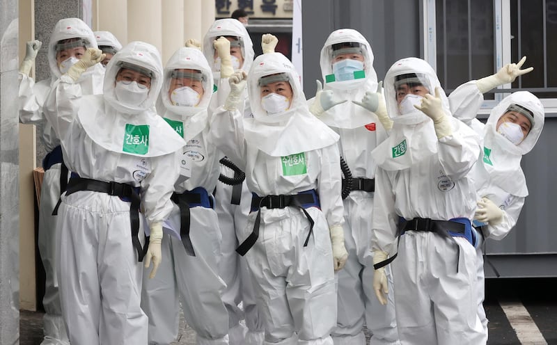 Medical staff members gesture as they arrive for a duty shift at Dongsan Hospital in Daegu, South Korea. Newsis via AP