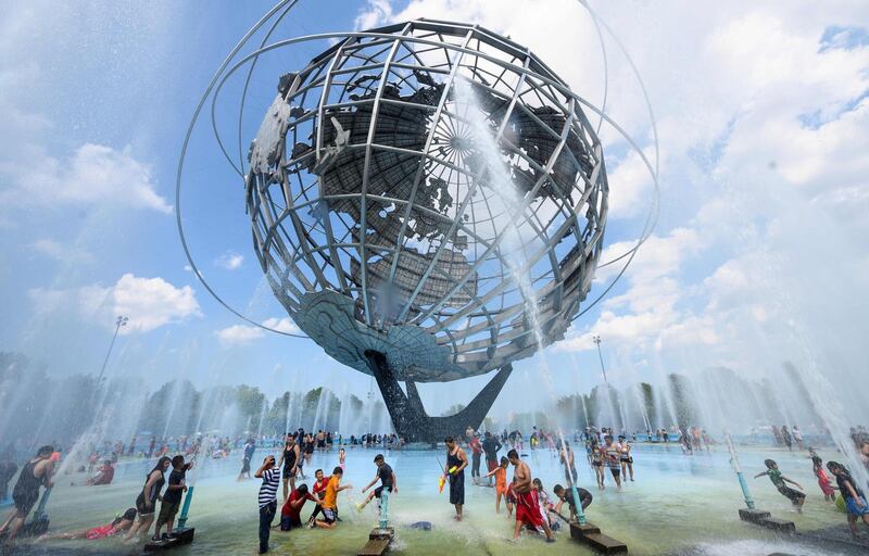 People enjoy refreshing water of a fountain in the Unisphere fountain at Flushing Meadow Corona Park  in the borough of Queens in New York City.   AFP