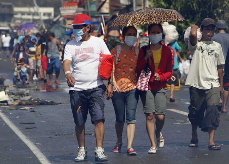 Survivors wearing face masks walk downtown after super Typhoon Haiyan battered Tacloban city. Romeo Ranoco / Reuters 