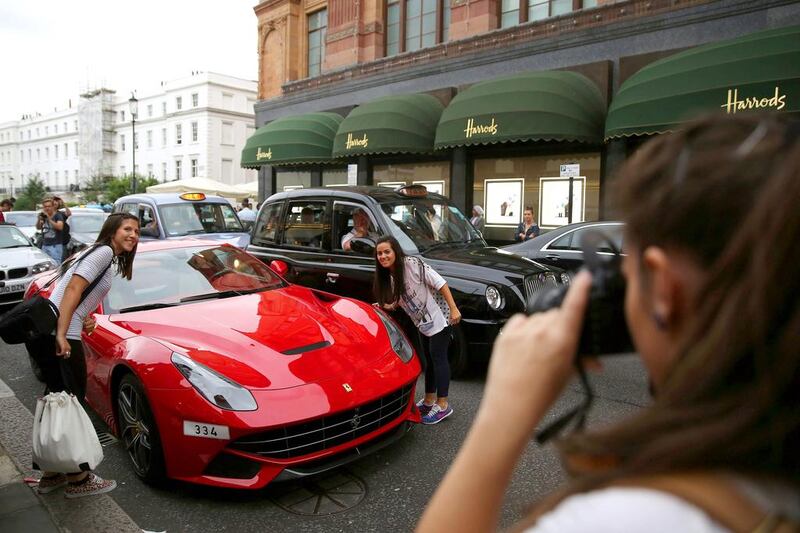 Car enthusiasts take a photograph of a Ferrari. Dan Kitwood / Getty Images