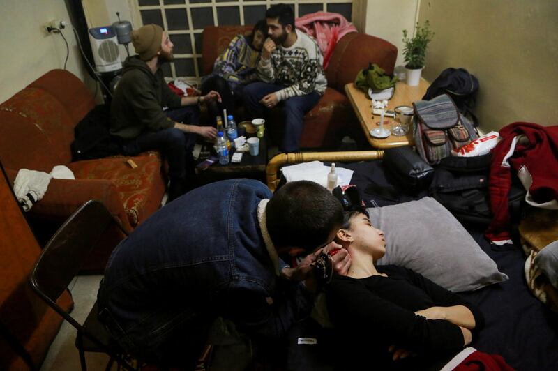 Aya, 24, a chef, rests as she gets a tattoo on her neck at her friend's house in Damascus. Reuters