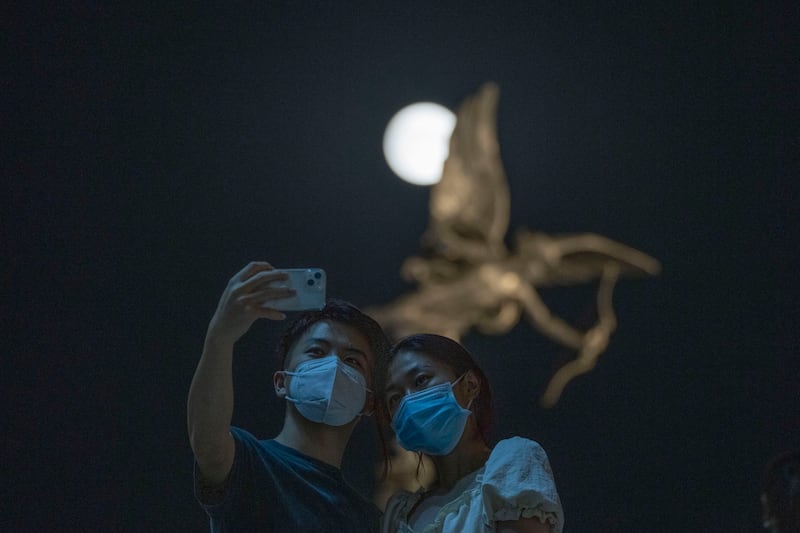 A moonlit moment for Beijing residents in front of a statue of Cupid. AP