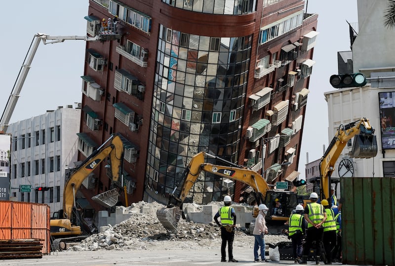 Workers carry out operations at the site where a building collapsed. Reuters