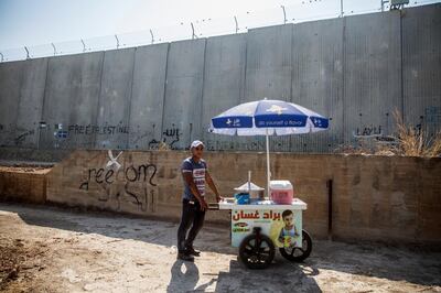 Twenty-two-year-old Islam Daoud stands with his lemonade stand nearby Israel's 8 meter high separation barrier in the Palestinian city of Qalqilya . He canÕt travel into Jerusalem or Israel without a permit. Mr Daoud lives in the West Bank city of Qalqilya, an agricultural area cut off from neighboring villages in Israel by the wall built in the mid-2000Õs. His grandfather, he said, had land now lost on the other side.
 
The youngest of eleven children, Mr Daoud finished high school and now makes ends meet selling plastic cups of iced lemon water for one shekel each.
 
HeÕs never voted before Ð the PA hasnÕt had elections in over a decade Ð and didnÕt know very much about the upcoming Israeli elections.
 
What he knows, he said, is that Òin the end the occupations remainsÉ In the end Palestine is occupied and the elections wonÕt change that.Ó (Photo by Heidi Levine for The National ).