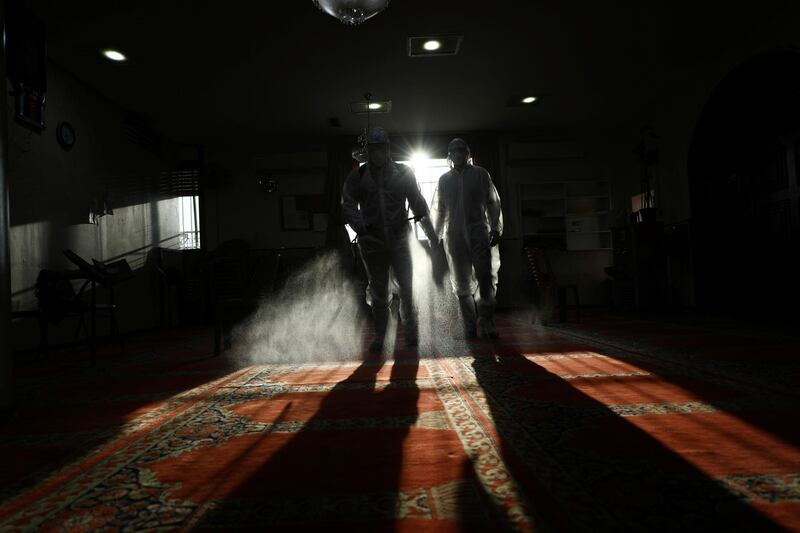 Palestinian volunteers wear protective gear as they sanitize a mosque in Jerusalem to help fight the coronavirus. Reuters