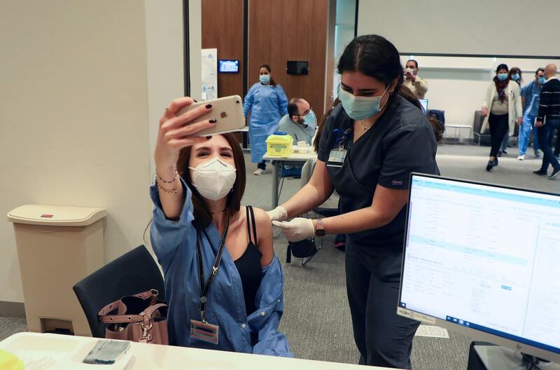 A woman takes a picture with her mobile phone as she receives the Pfizer/BioNTech vaccine at American University of Beirut's medical centre, Lebanon. Reuters