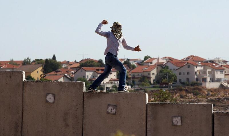 A file photo of a Palestinian youth stands on top of Israel's separation barrier as he throws stones at Israeli forces (unseen) during a weekly protest in the West Bank village of Nilin. Israeli prime minister Benjamin Netanyahu has suggested hardening the rules towards Palestinian stone-throwers. Abbas Momani/AFP Photo

