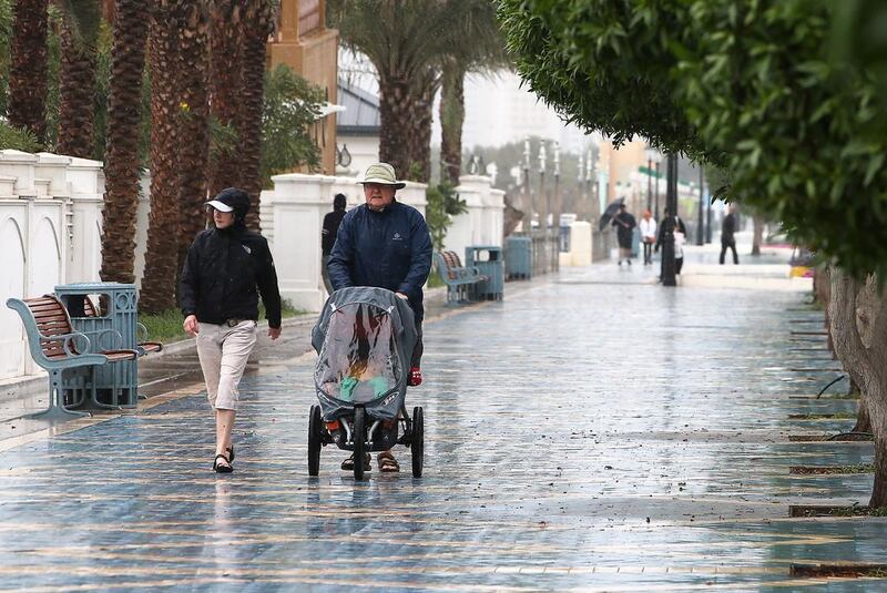 People walk on rain-slicked streets in Abu Dhabi. Pawan Singh / The National