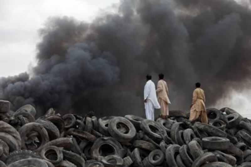 Dubai, January 11, 2011 - Bystanders watch as a tire fire at Emirates Recycling burns in the background in Al Qusais, Dubai January 11, 2010. (Jeff Topping/The National) 