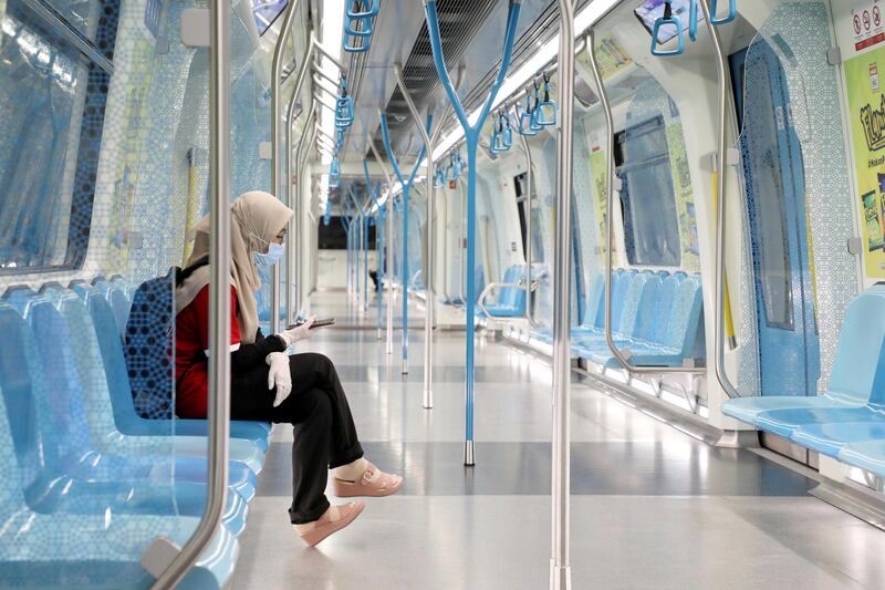 A woman wearing protective mask and gloves uses her phone in a Mass Rapid Transit train, during the movement control order due to the outbreak of coronavirus in Kuala Lumpur, Malaysia. Reuters