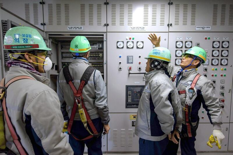 Workers stand before instrument panels in the engine control room of an under-construction Maersk triple-E class container ship. Ed Jones / AFP