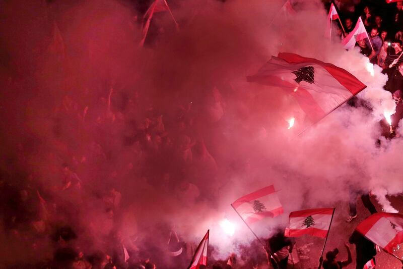 Anti-government protesters light flares and wave Lebanese national flag in Beirut. AP Photo