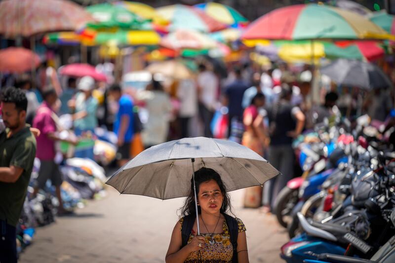 A woman walks under an umbrella as a heatwave grips Guwahati, India. AP