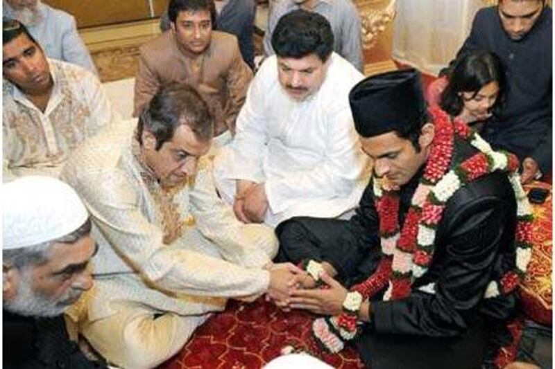 A garlanded Shoaib Malik holds hands with Imran Mirza, his bride's father, during the wedding ceremony in Hyderabad yesterday.