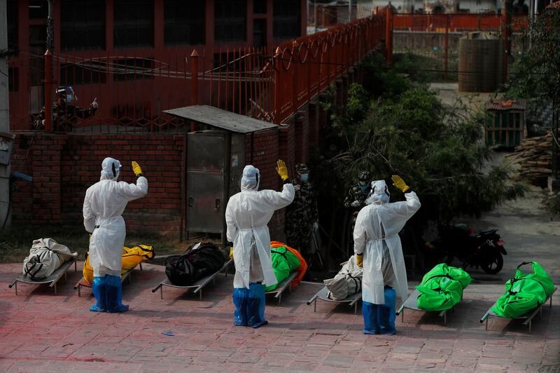 Nepalese army personnel in PPE suits salute Covid-19 victims before cremating their bodies near Pashupatinath temple in Kathmandu, Nepal. Coronavirus cases have hit record numbers, with hospitals running out of beds and oxygen. AP Photo