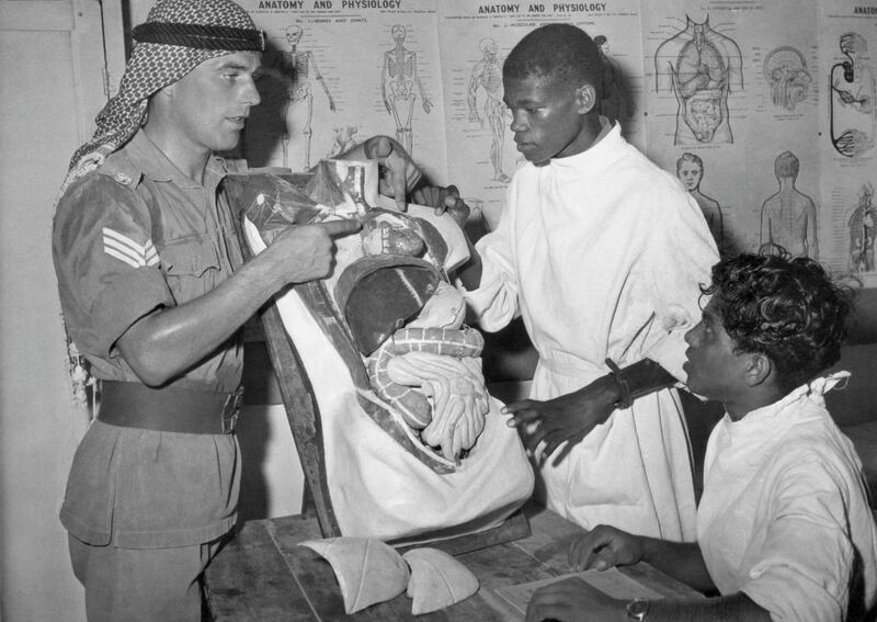 Staff Sergeant John P. Hindley, left, of Blackburn, Lancs, a British N.C.O serving with the Trucial Oman Scouts, uses a cutaway model of the human body as he instructs two Arab medical orderlies at the Scouts' headquarters in Sharjah, on Aug. 9, 1961. The model is used to explain the workings of the body. A British-financed defense force, the Scouts were formed 10 years ago to maintain security in the seven independent Sheikhdoms known as the Trucial states. (AP Photo)