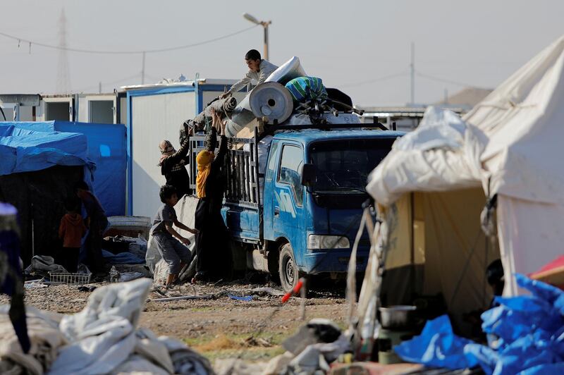 Displaced Iraqis load their belongings on to a lorry as they prepare to leave Hammam Al Alil camp. Reuters