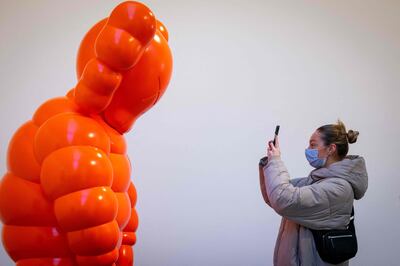 A visitor photographs an artwork by Kaws at the Serpentine Galleries in London. AFP 