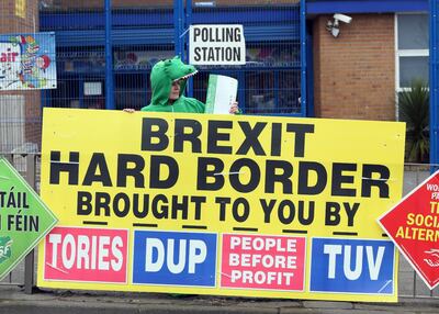 (FILES) In this file photo taken on March 2, 2017 a Sinn Fein party election worker dressed up as a crocodile stands behind a banner referring to Brexit outside a polling station in Belfast as voters in Northern Ireland go to the polls to elect a new Assembly. Northern Ireland marks its 100th year on Monday, May 3, but faltering efforts to commemorate the centenary encapsulate the rift at the heart of the British province. / AFP / Paul FAITH / TO GO WITH AFP STORY BY JOE STENSON
