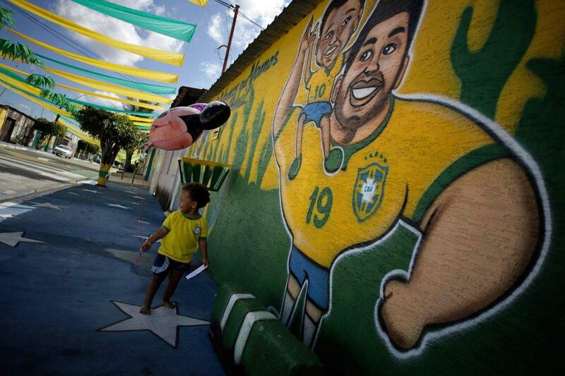 A child walks in a street decorated for the upcoming 2014 World Cup with a mural of Brazil player Hulk in view. Eraldo Peres / AP / June 4, 2014