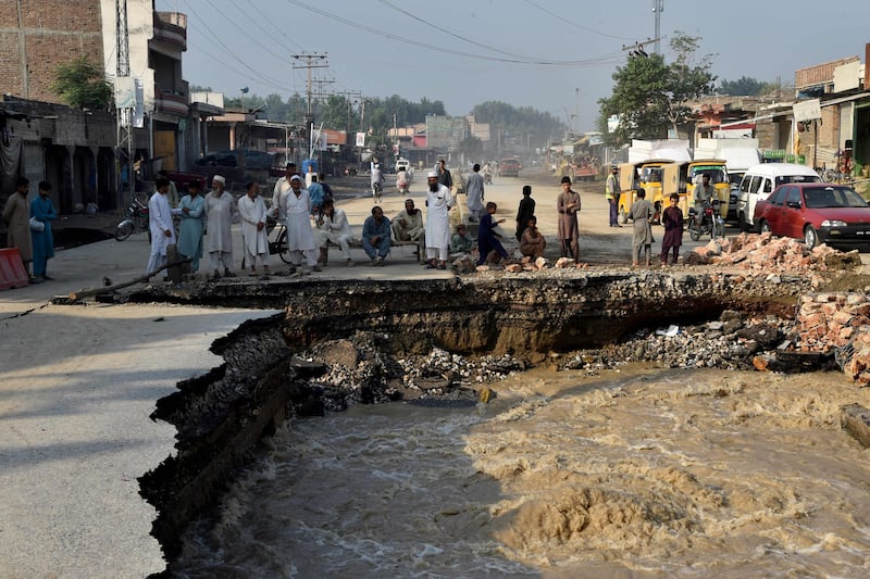 Residents gather beside a road damaged by floodwater after heavy monsoon rain in the Charsadda district of Khyber Pakhtunkhwa. The death toll from monsoon flooding in Pakistan since June has reached 1,061 to date, the country's National Disaster Management Authority said. AFP