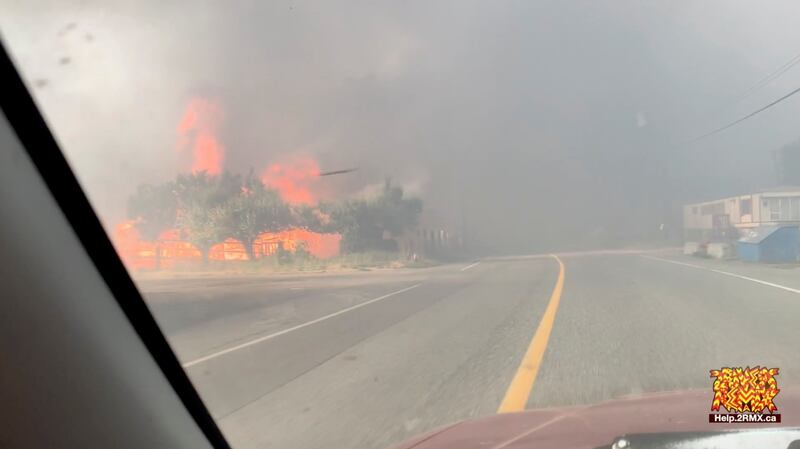 Flames are seen along a street during a wildfire in Lytton, British Columbia in this still image obtained from a social media video.