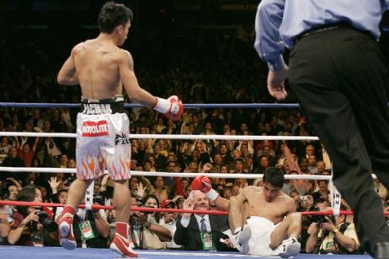 Manny Pacquiao (L) of the Philippines sends Erik Morales of Mexico to the mat for the third time during their super featherweight fight at the Thomas & Mack Center in Las Vegas, Nevada, November 18, 2006. REUTERS/Steve Marcus (UNITED STATES)