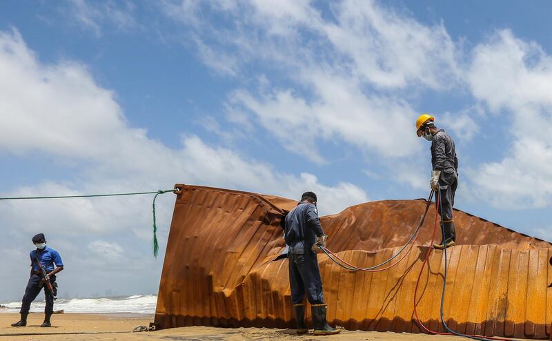 Sri Lankan Navy personnel try to remove damaged containers. EPA