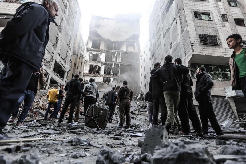 Palestinians gather in front of damaged buildings in Gaza City following Israeli air strikes. AFP Photo