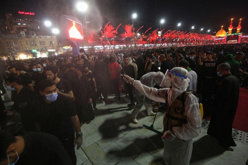 A worker sprays disinfectant as worshippers gather near the Imam al-Abbas Shrine. AFP