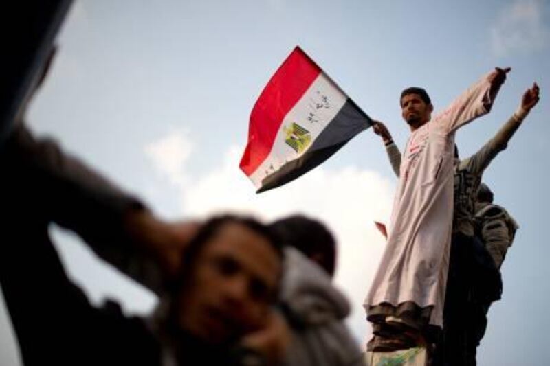 TOPSHOTS
An Egyptian protester waves his national flag as he stands on a lamp post with other demonstrators during a mass rally demanding an end to military rule at Tahrir Square in Cairo on November 25, 2011. Egypt's new prime minister Kamal al-Ganzuri, 79, is a former premier and veteran economist, but his appointment is not likely to satisfy mass calls for a fresh face to lead the country to democratic rule.     AFP PHOTO/ ODD ANDERSEN
 *** Local Caption ***  345235-01-08.jpg