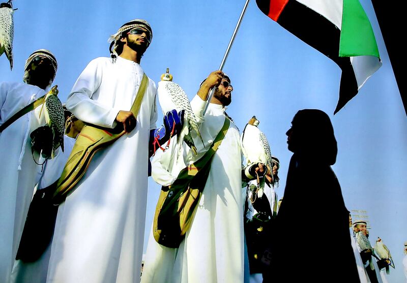 Falconers wave the UAE flag at the Abu Dhabi International Hunting and Equestrian Exhibition. Victor Besa / The National