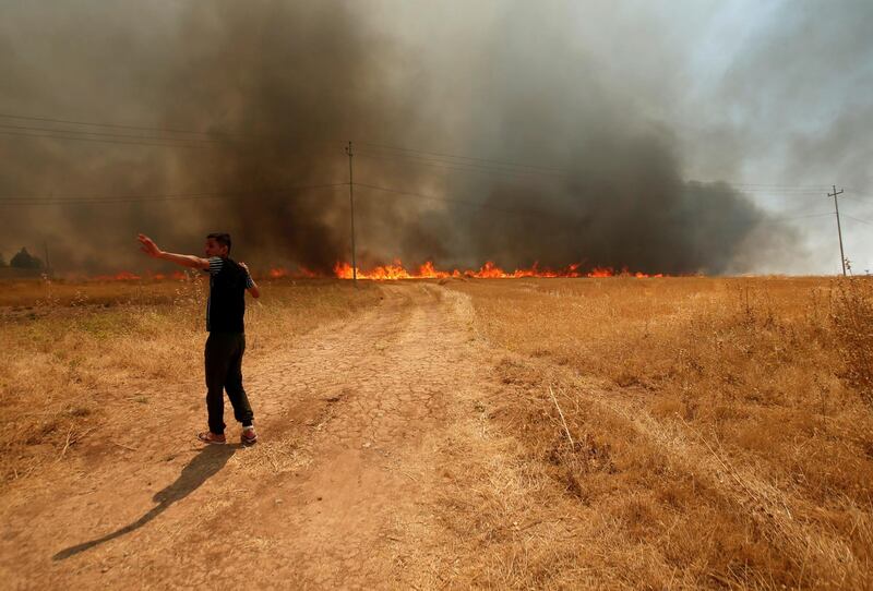 A man asks for help to put out a fire that engulfed a wheat field in the northern town of Bashiqa, east of Mosul, Iraq. Reuters