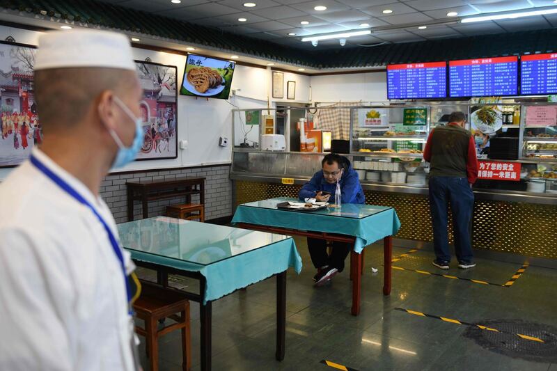 A man eats in a restaurant that has only one seat per table and markings on the floor to enforce social distancing in Beijing. AFP