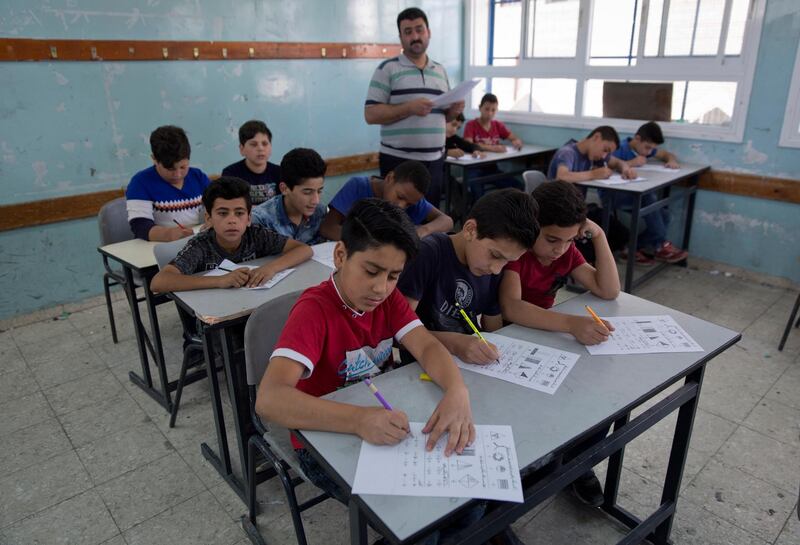A teacher supervises while Palestinian school children attend a final exam during the last day of the school year. AP Photo
