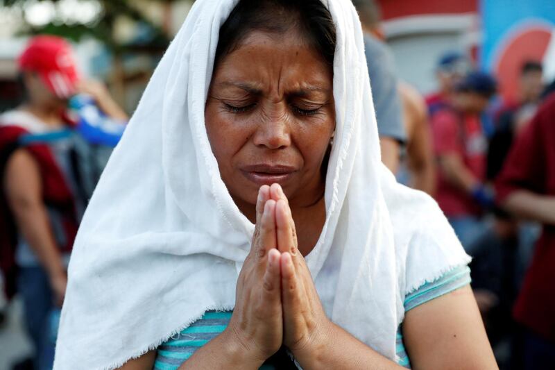 A migrant from El Salvador prays near the border gate between Guatemala and Mexico, in Tecun Uman, Guatemala. Reuters