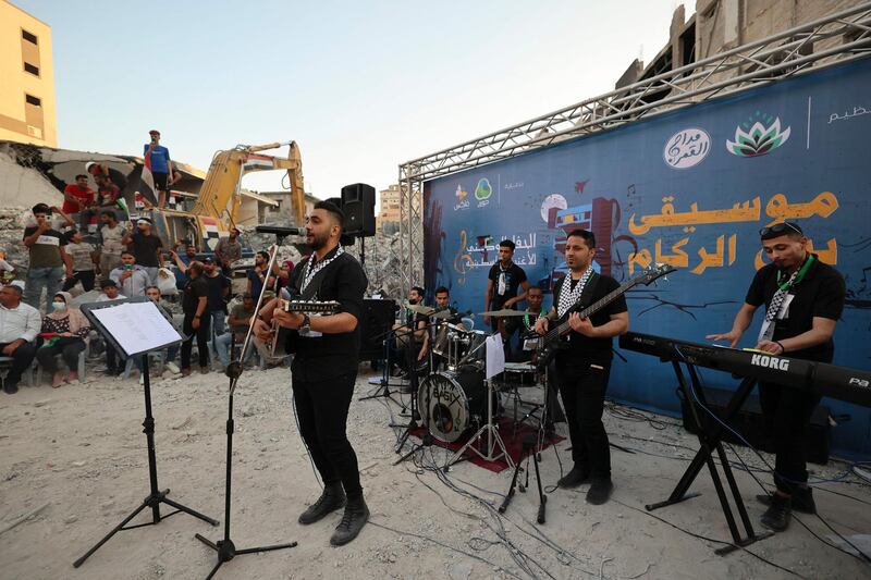 Musicians in Gaza city's Al Rimal neighbourhood perform in front of the remains of Al Shuruq Tower, which was levelled by an Israeli air strike during last month's conflict. AFP