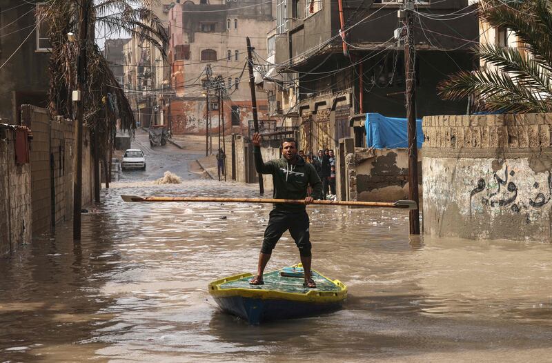 A Palestinian man rides a paddle board on a flooded street after heavy rain at Al Shati refugee camp in the Gaza strip. AFP