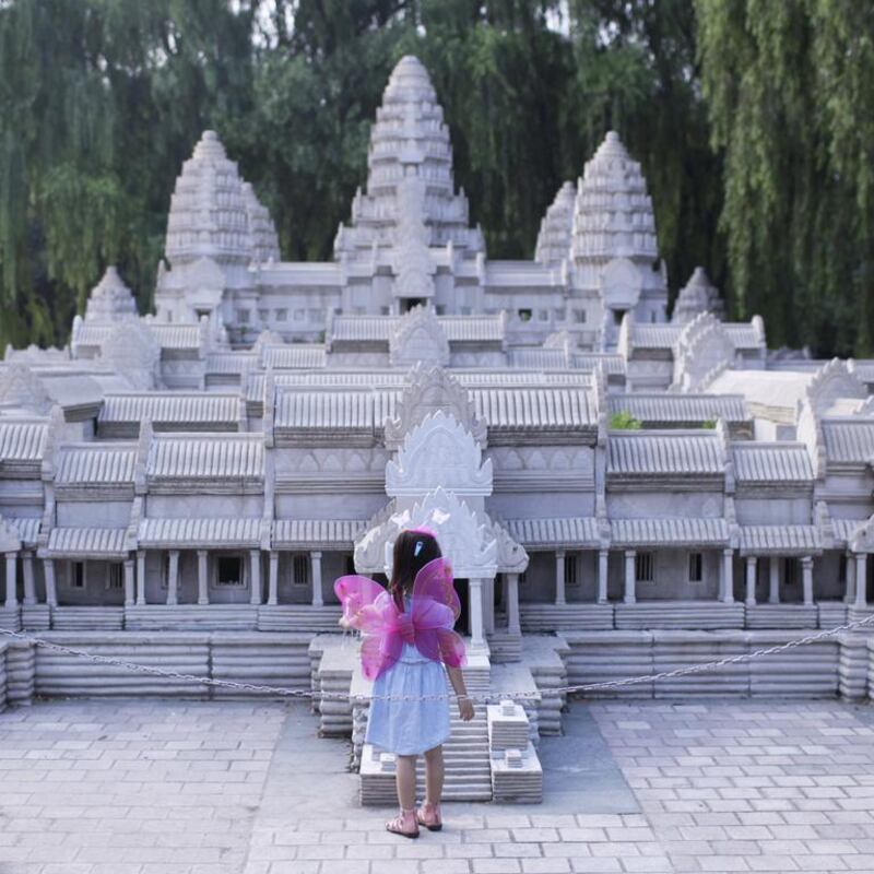 A little girl standing before a mini replica of Angkor Wat.