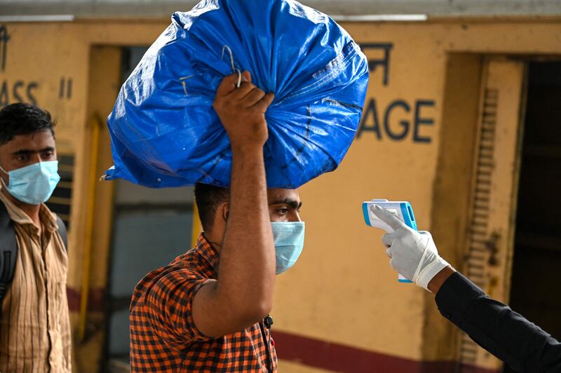 A temperature check for a passenger who has disembarked from a long-distance train in Mumbai.  AFP